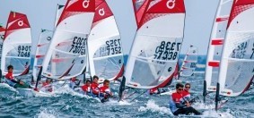 Régate de voiliers Optimist en mer, jeunes navigateurs en course avec voiles rouges et blanches numérotées 7338 et 7352.