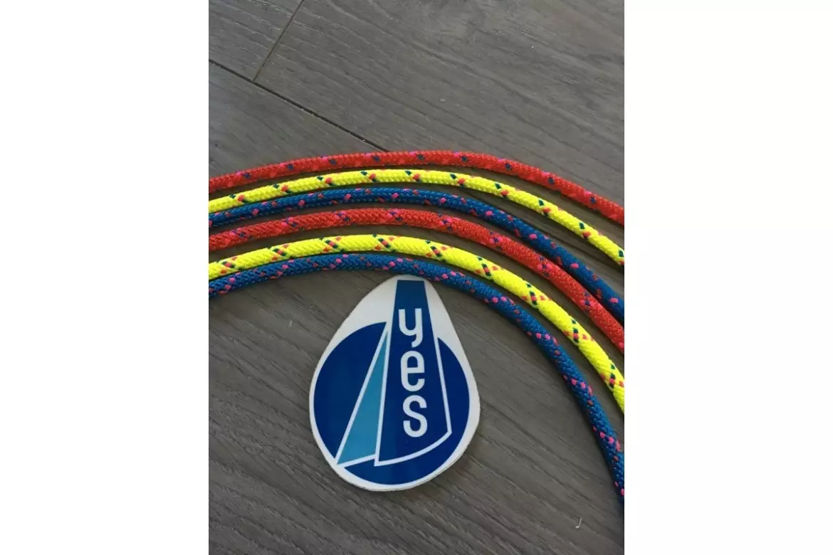 Cordages nautiques rouge, jaune et bleu avec autocollant YES et logo voile sur un sol gris.