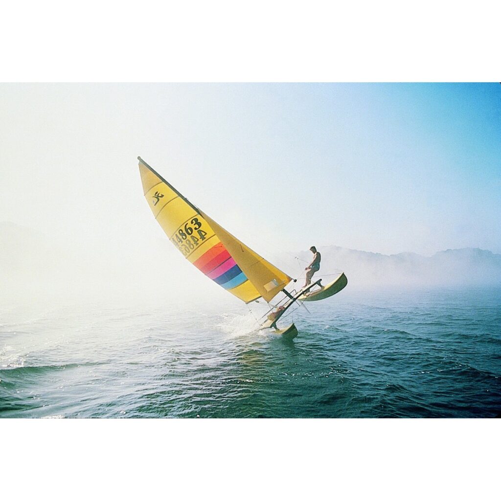 Catamaran en Navigation Sportive : Voile Jaune et Brume Catamaran Hobie Cat volant sur une coque, voile jaune arc-en-ciel 44863, navigation sportive dans la brume.